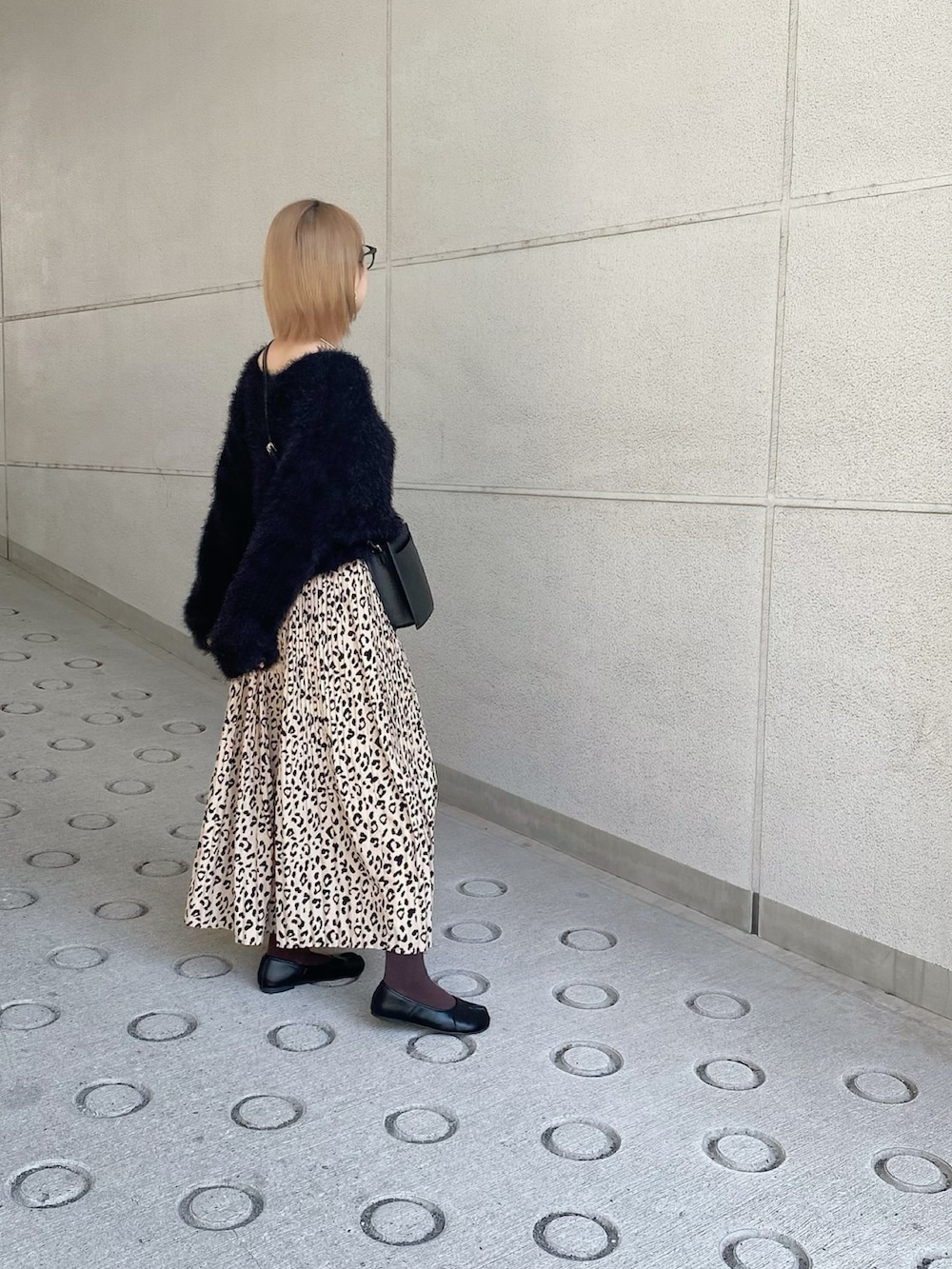 ブラック系のニット/セーター、ブラック系のショルダーバッグ、ベージュ系のスカートを着用したレディースの秋コーディネートの4枚目の写真