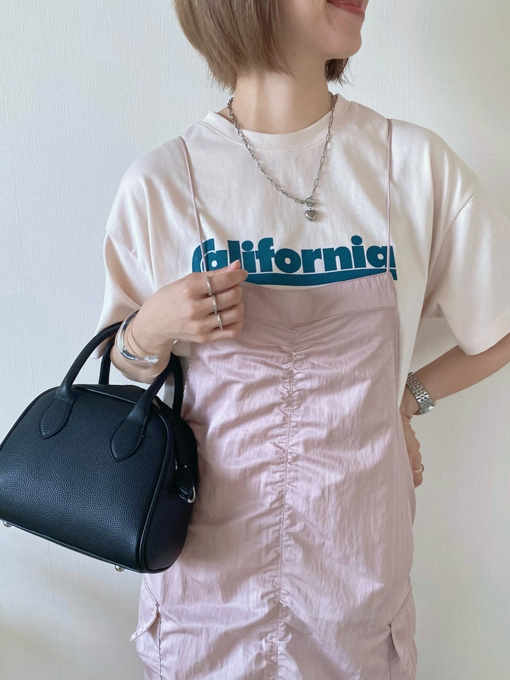 ブラック系のボストンバッグ、ピンク系のワンピース、ベージュ系のTシャツ/カットソーを着用したレディースの夏コーディネートの3枚目の写真
