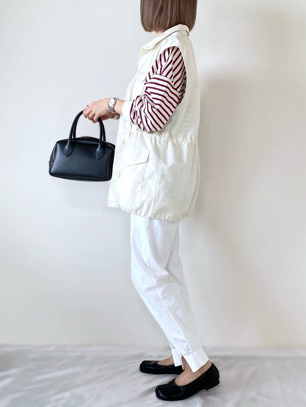 レッド系のTシャツ/カットソー、ホワイト系のベスト、ホワイト系のその他パンツを着用したレディースの冬コーディネートの3枚目の写真