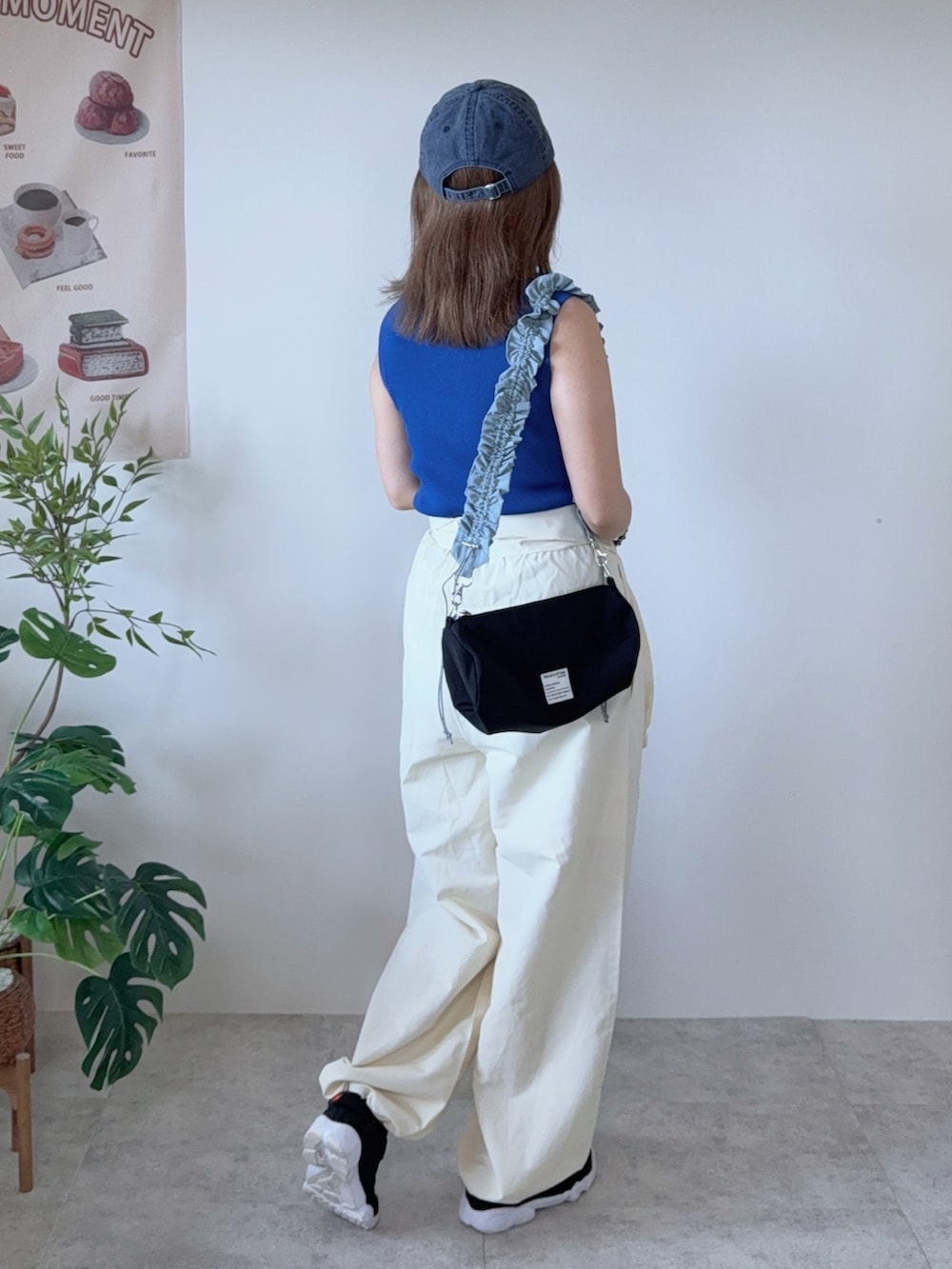 ブルー系のニット/セーター、ブラック系のショルダーバッグ、ブラック系のスニーカーを着用したレディースの春コーディネートの3枚目の写真