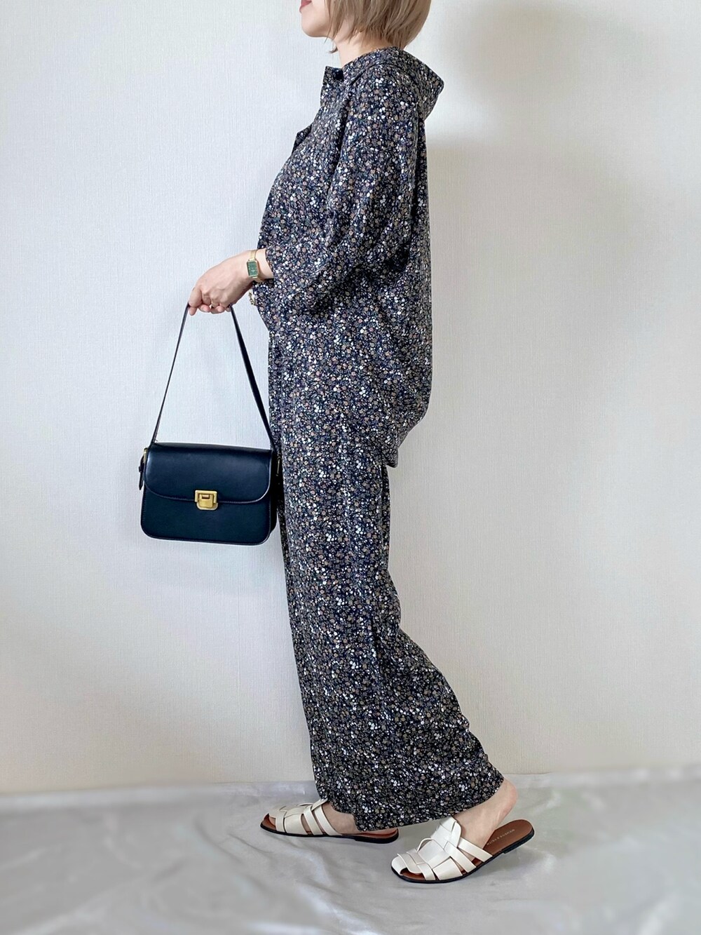 ブラック系のショルダーバッグ、ホワイト系のサンダル、ブラック系のシャツ/ブラウスを着用したレディースの夏コーディネートの2枚目の写真