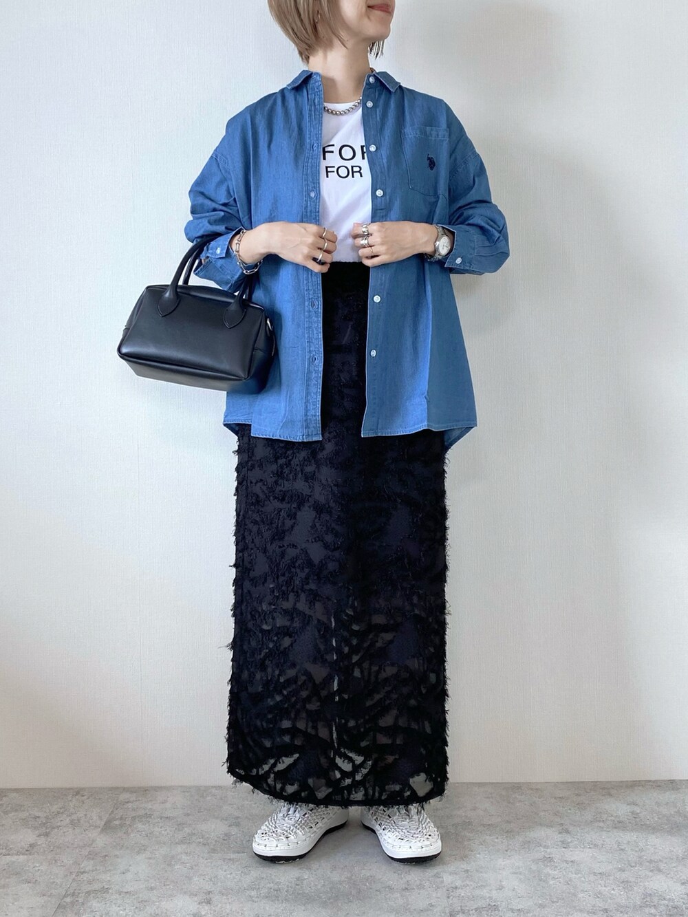 ブラック系のバッグ、ブラック系のスカート、ホワイト系のシューズを着用したレディースの夏コーディネートの2枚目の写真