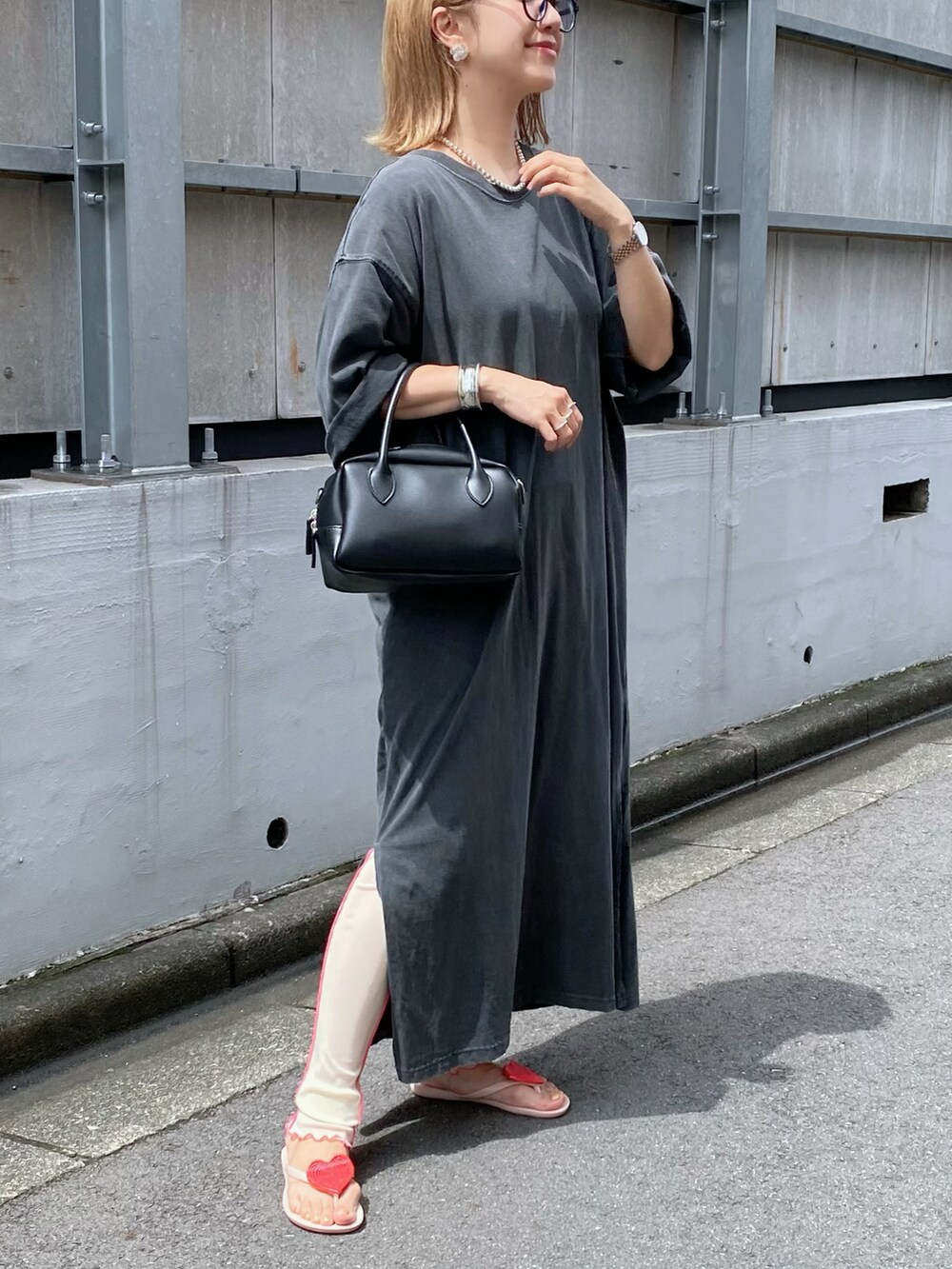 ピンク系のサンダル、ブラック系のバッグ、シルバー系のピアス（両耳用）を着用したレディースの夏コーディネートの2枚目の写真