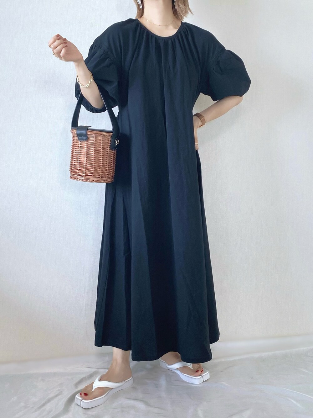 ブラック系のワンピース、ブラック系のバッグ、ホワイト系のサンダルを着用したレディースの春コーディネートの2枚目の写真