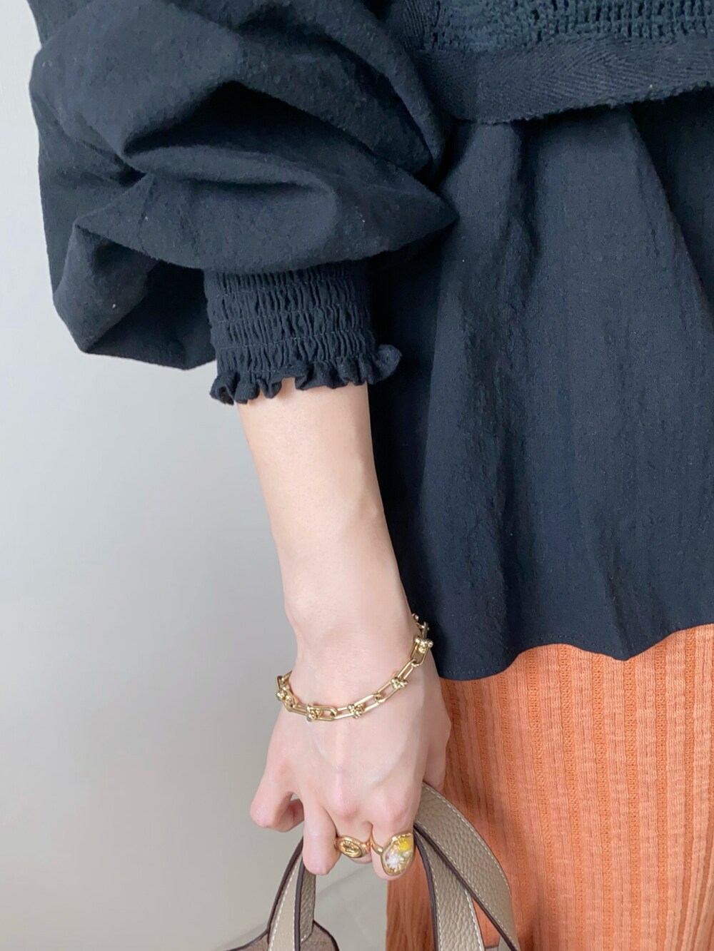 オレンジ系のスカート、ベージュ系のローファー、ブラック系のシャツ/ブラウスを着用したレディースの春コーディネートの4枚目の写真