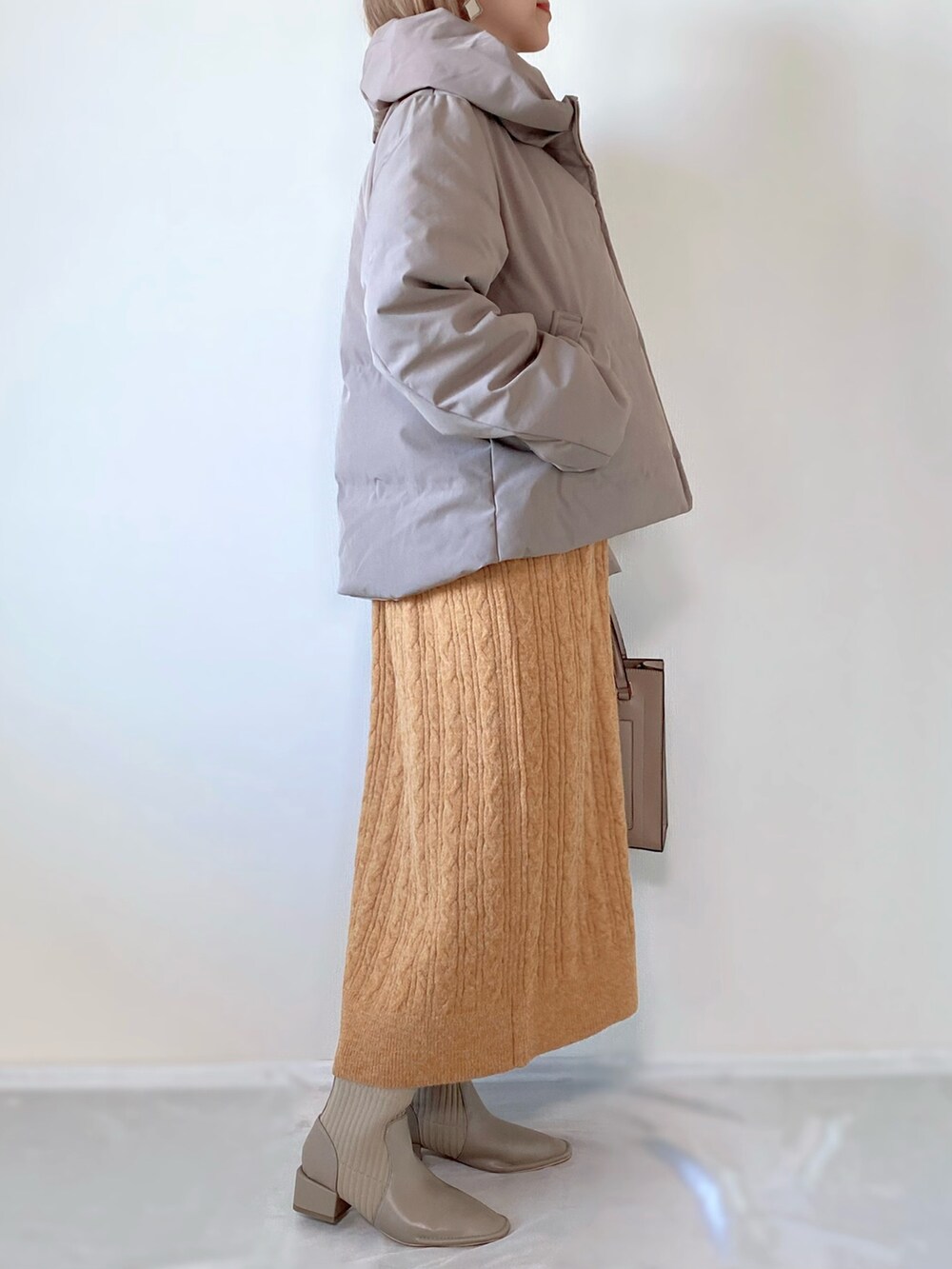 ブラウン系のダウンジャケット/コート、オレンジ系のワンピース、ベージュ系のバッグを着用したレディースの秋コーディネートの3枚目の写真