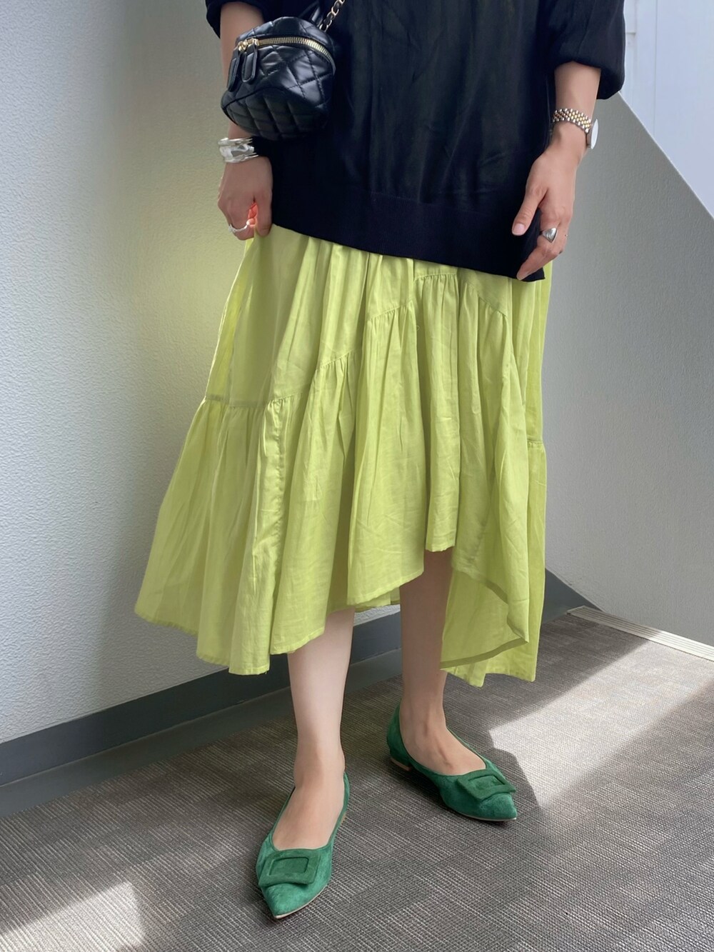 グリーン系のパンプス、イエロー系のワンピース、ブラック系のショルダーバッグを着用したレディースの夏コーディネートの3枚目の写真