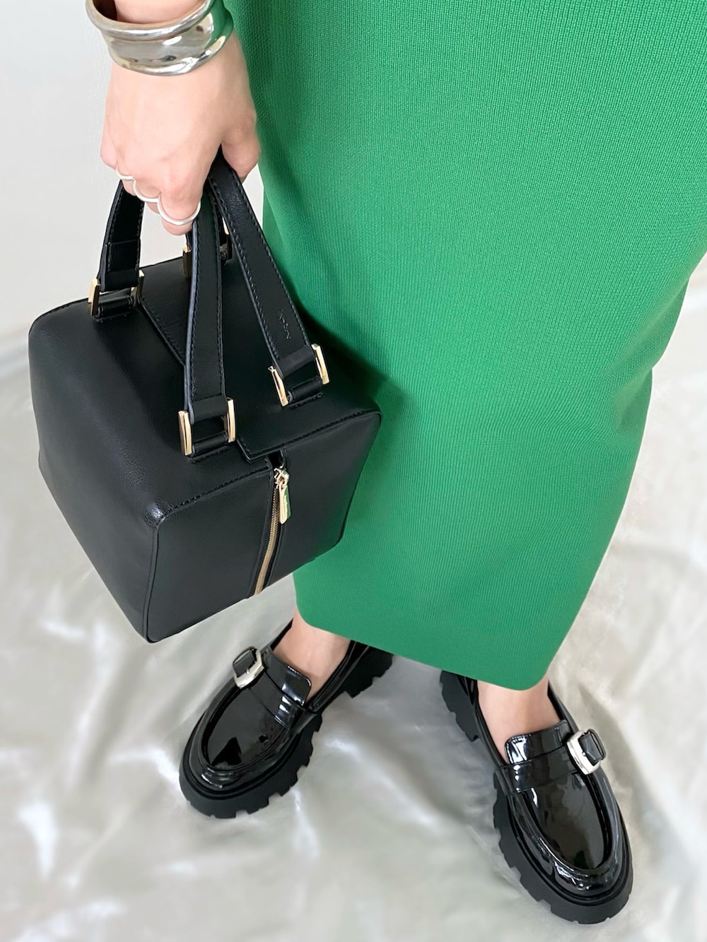 ブラック系のハンドバッグ、ベージュ系のTシャツ/カットソー、グリーン系のスカートを着用したレディースの秋コーディネートの4枚目の写真