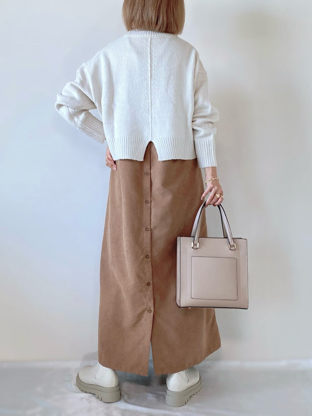 ホワイト系のニット/セーター、ブラウン系のワンピース、ホワイト系のブーツを着用したレディースの秋コーディネートの3枚目の写真