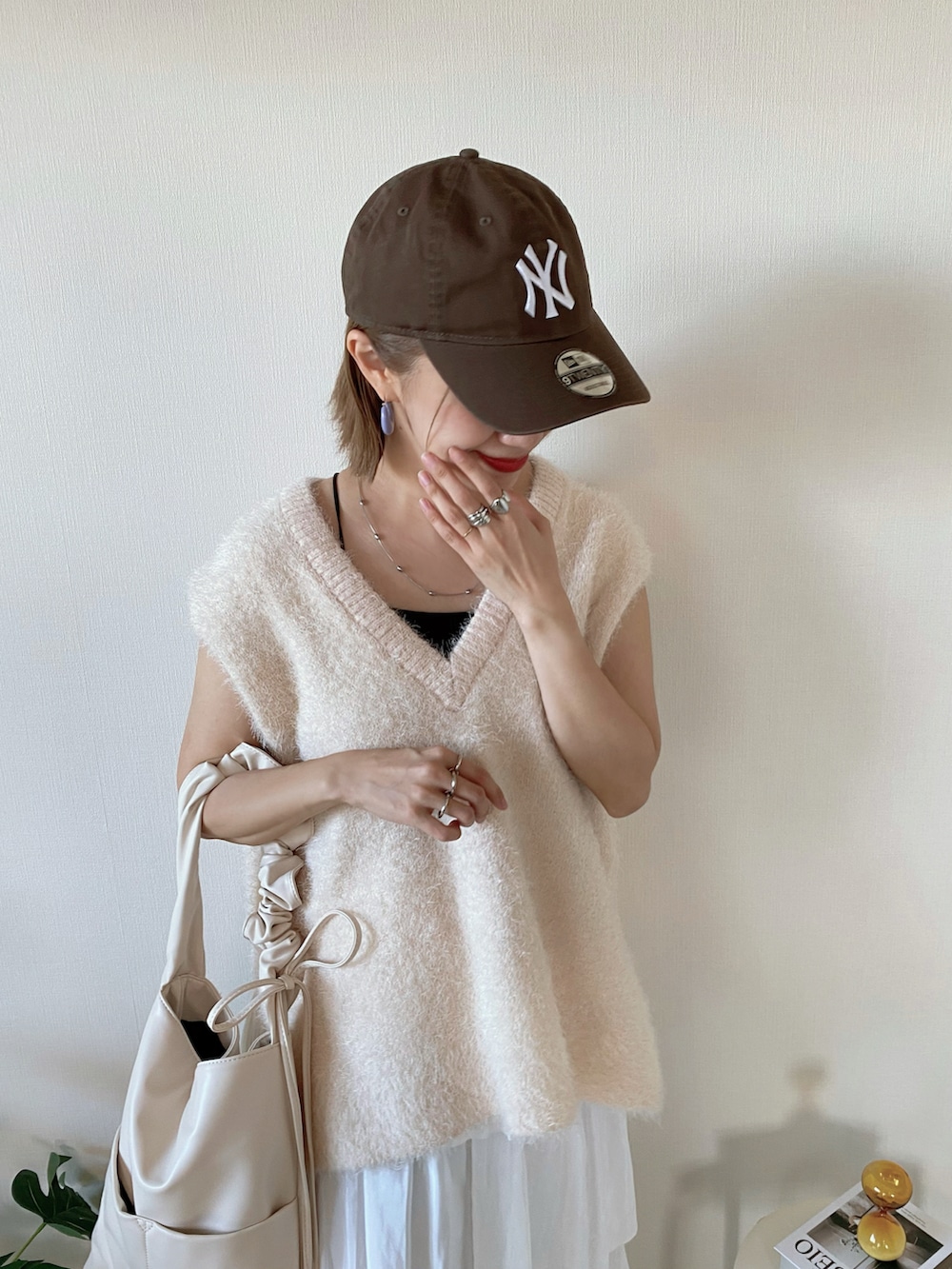 ホワイト系のベスト、ゴールド系のスニーカー、ホワイト系のスカートを着用したレディースの秋コーディネートの4枚目の写真