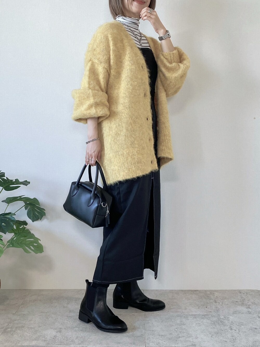 ブラック系のワンピース、ブラック系のブーツ、ブラック系のバッグを着用したレディースの冬コーディネートの2枚目の写真