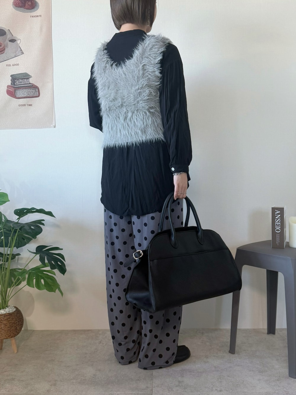 ベージュ系のベスト、ブラック系のボストンバッグ、グレー系のパンツを着用したレディースの冬コーディネートの2枚目の写真