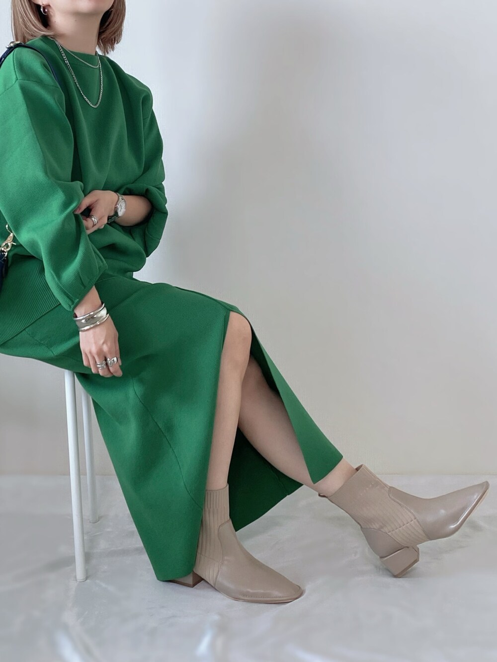 グリーン系のニット/セーター、グリーン系のスカート、ベージュ系のブーツを着用したレディースの秋コーディネートの2枚目の写真