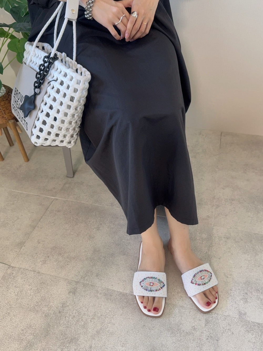 ホワイト系のサンダル、ホワイト系のかごバッグ、シルバー系のネックレスを着用したレディースの夏コーディネートの3枚目の写真