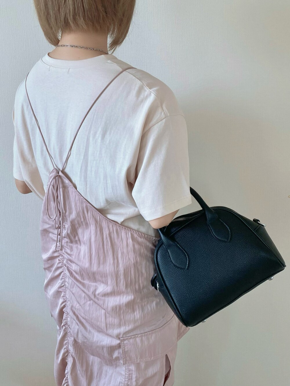 ブラック系のボストンバッグ、ピンク系のワンピース、ベージュ系のTシャツ/カットソーを着用したレディースの夏コーディネートの4枚目の写真