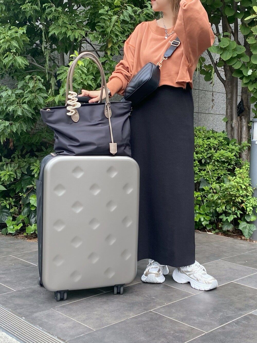 ブラック系のワンピース、ゴールド系のスニーカー、ブラック系のバッグを着用したレディースの秋コーディネートの2枚目の写真