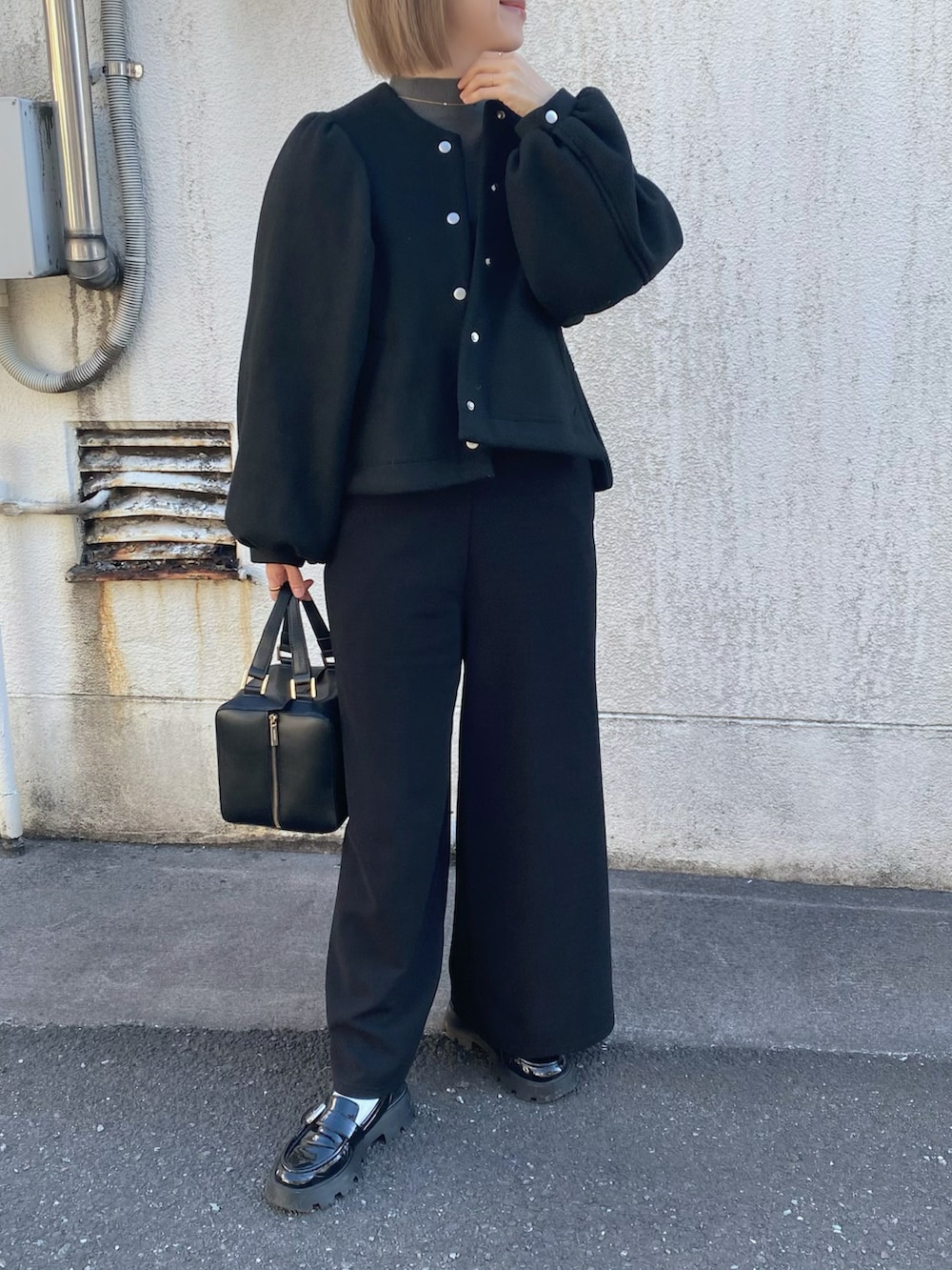 グレー系のニット/セーター、ブラック系のハンドバッグ、ブラック系のローファーを着用したレディースの冬コーディネートの4枚目の写真