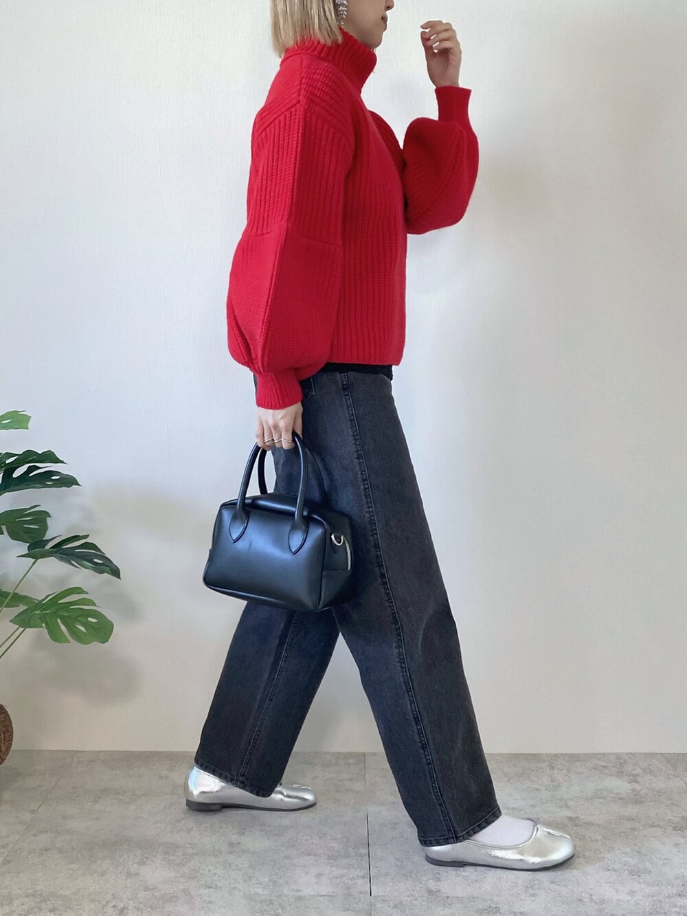 レッド系のニット/セーター、ブラック系のデニムパンツ、ブラック系のバッグを着用したレディースの冬コーディネートの2枚目の写真