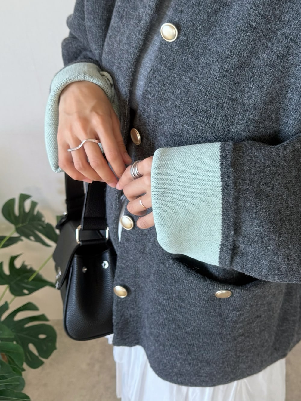 グレー系のカーディガン/ボレロ、ホワイト系のスカート、ブラック系のショルダーバッグを着用したレディースの秋コーディネートの5枚目の写真