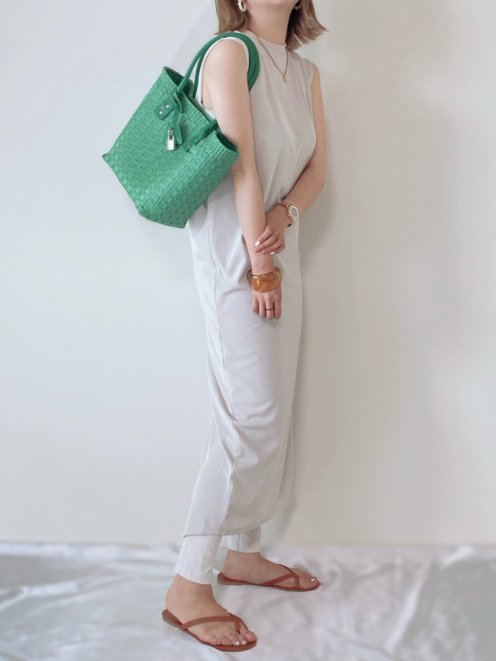 グリーン系のバッグ、ベージュ系のワンピースを着用したレディースの夏コーディネートの3枚目の写真