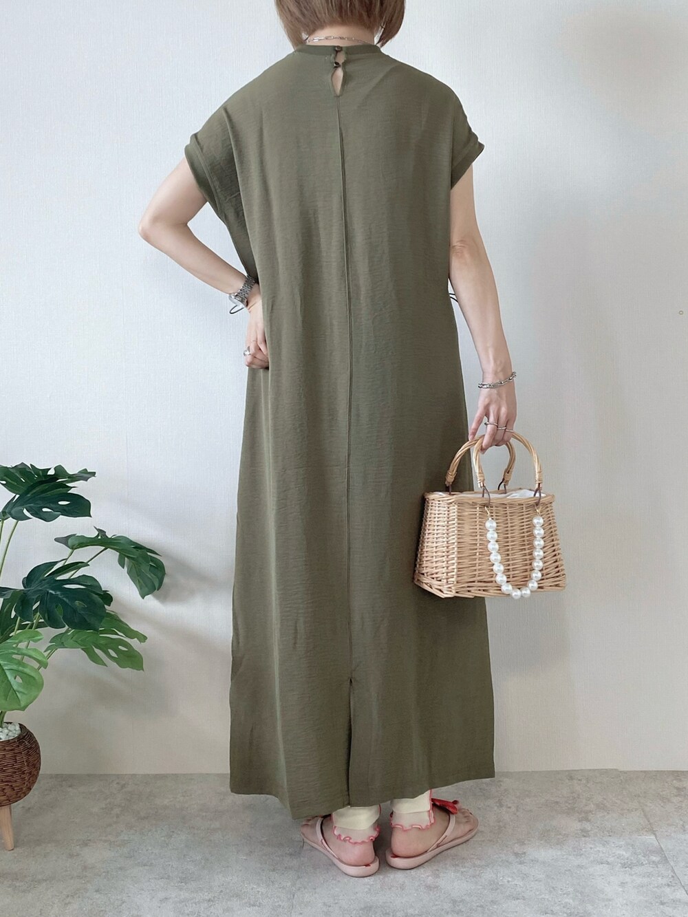 ベージュ系のかごバッグ、グリーン系のワンピース、ピンク系のサンダルを着用したレディースの夏コーディネートの3枚目の写真