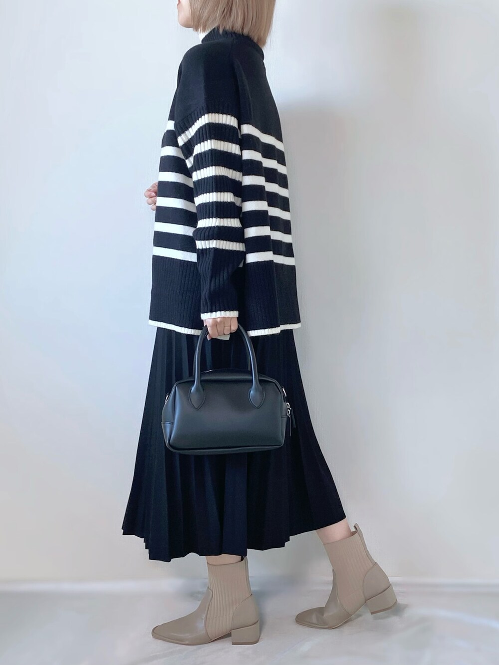 ブラック系のバッグ、ブラック系のニット/セーター、ベージュ系のブーツを着用したレディースの冬コーディネートの3枚目の写真