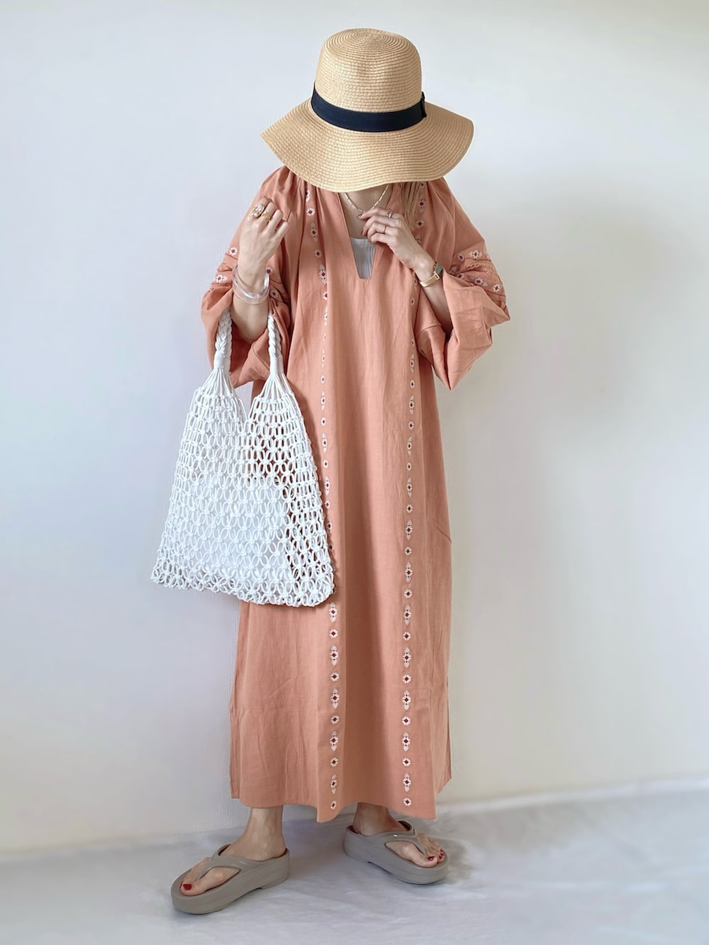 ホワイト系のかごバッグ、ピンク系のワンピース、ベージュ系のサンダルを着用したレディースの春コーディネートの2枚目の写真