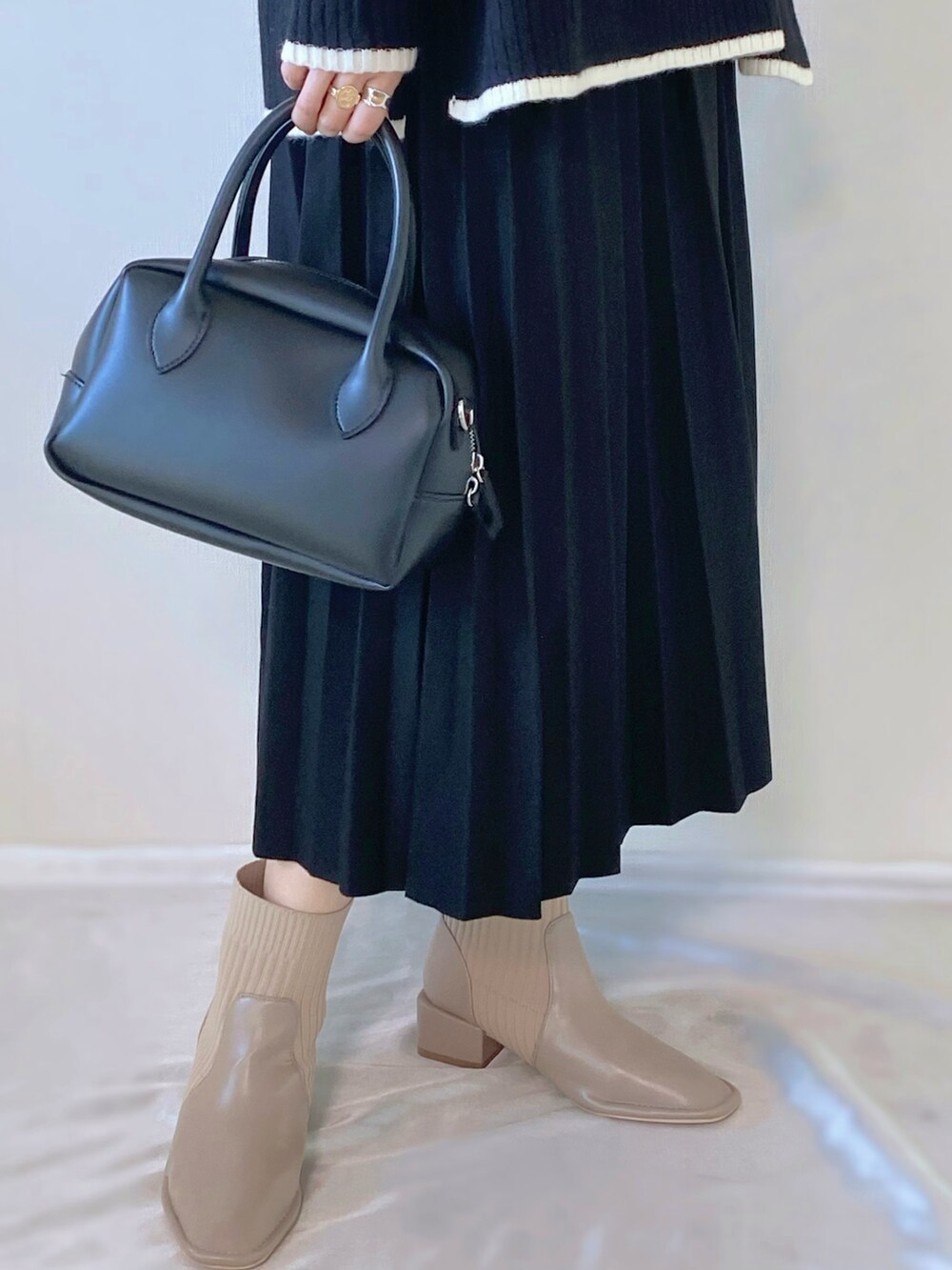 ブラック系のバッグ、ブラック系のニット/セーター、ベージュ系のブーツを着用したレディースの冬コーディネートの4枚目の写真