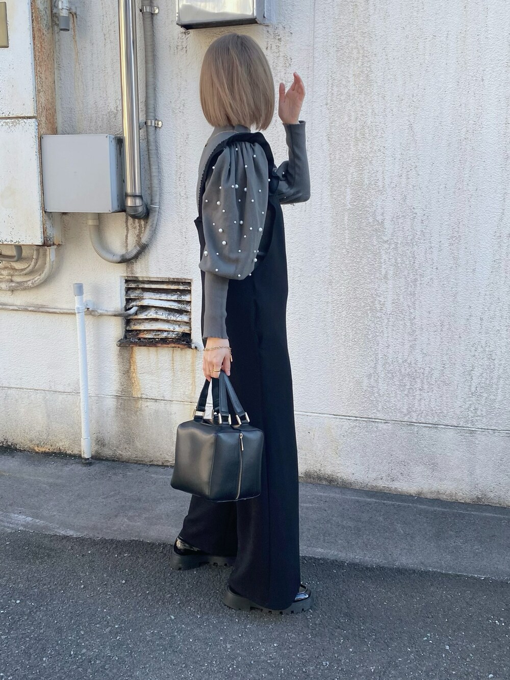 グレー系のニット/セーター、ブラック系のハンドバッグ、ブラック系のローファーを着用したレディースの冬コーディネートの3枚目の写真