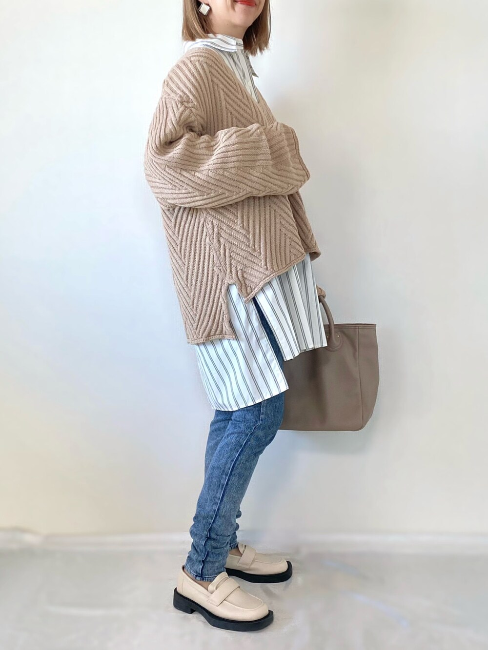 ベージュ系のニット/セーター、ホワイト系のシャツ/ブラウス、ベージュ系のバッグを着用したレディースの冬コーディネートの3枚目の写真