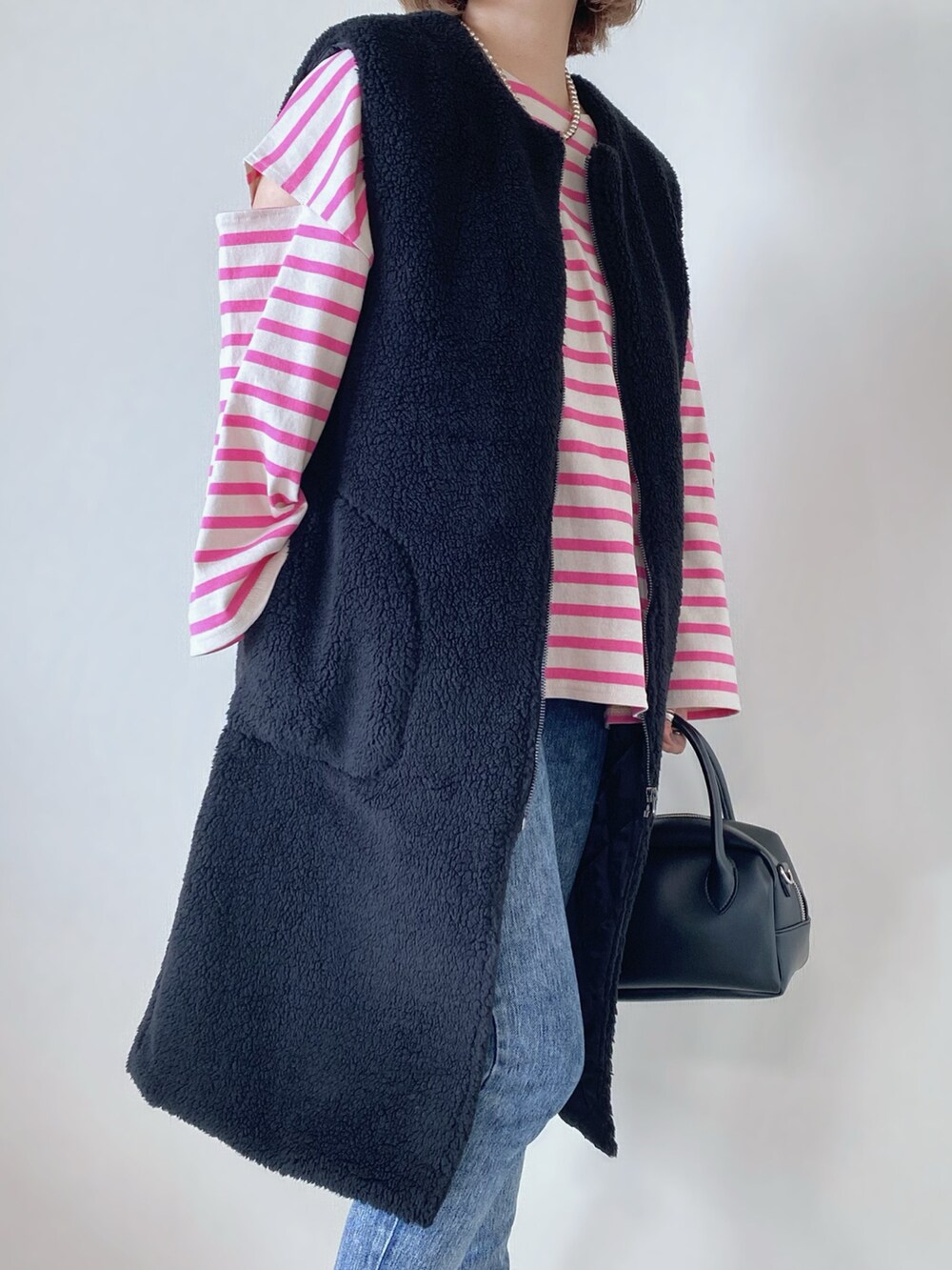 ブラック系のベスト、ピンク系のTシャツ/カットソー、ブラック系のバッグを着用したレディースの秋コーディネートの4枚目の写真