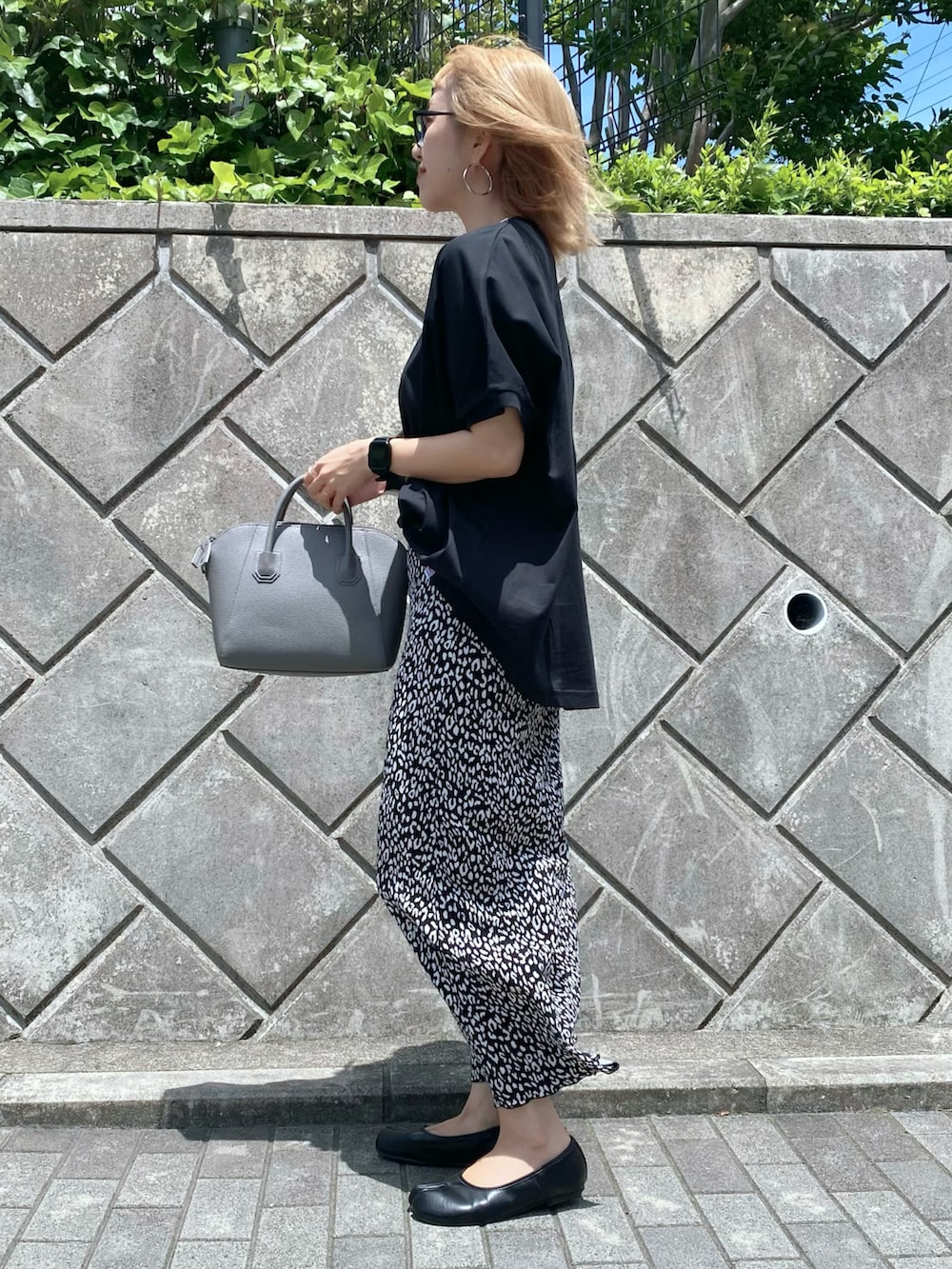 ブラック系のスカート、ブラック系のパンプス、グレー系のハンドバッグを着用したレディースの夏コーディネートの2枚目の写真