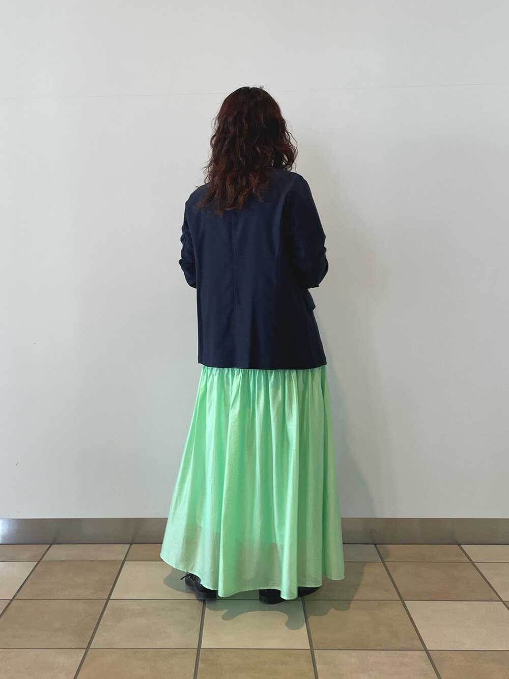 ブルー系のテーラードジャケット、ホワイト系のTシャツ/カットソー、グリーン系のスカートを着用したレディースの春コーディネートの3枚目の写真