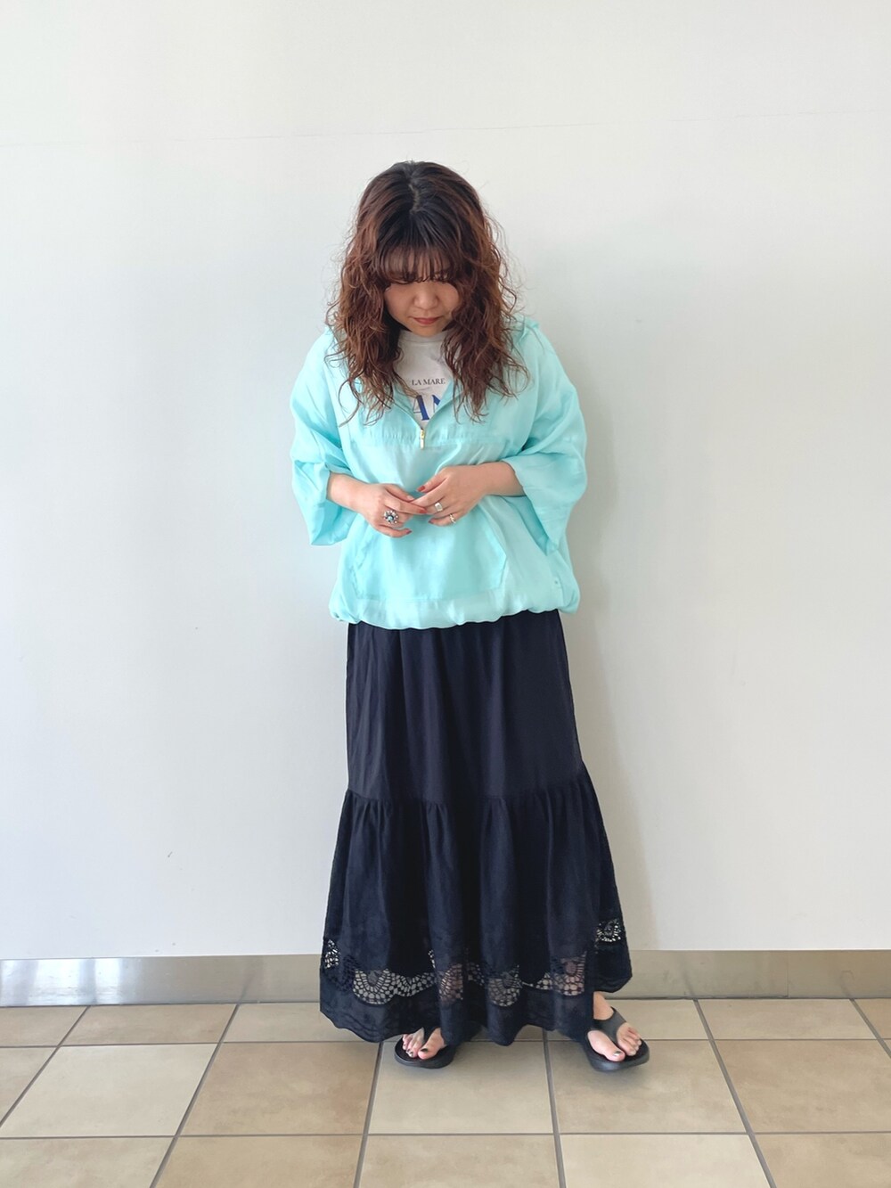 ブルー系のTシャツ/カットソー、ブラック系のスカート、ブラック系のサンダルを着用したレディースの春コーディネートの2枚目の写真