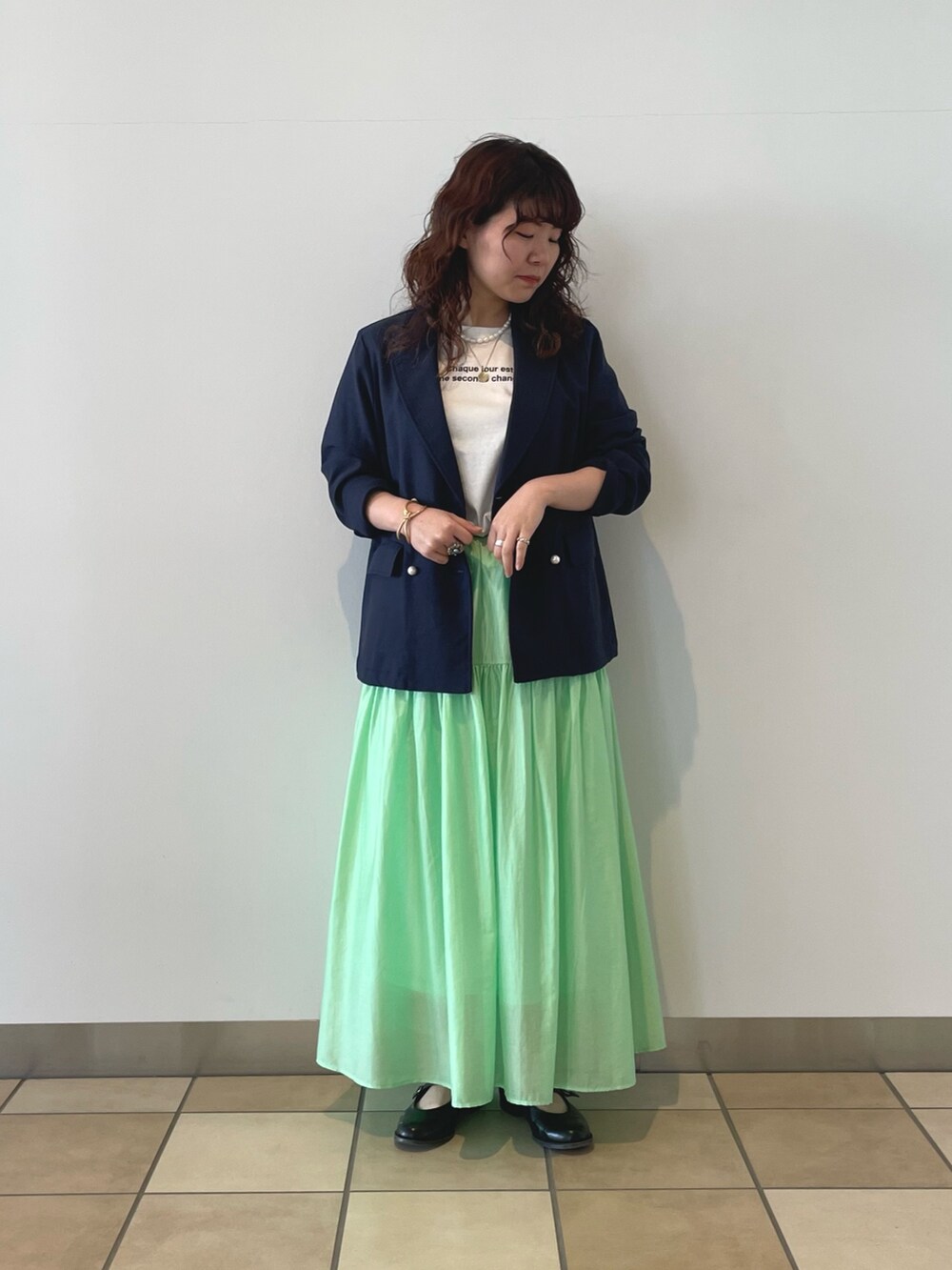 ブルー系のテーラードジャケット、ホワイト系のTシャツ/カットソー、グリーン系のスカートを着用したレディースの春コーディネートの2枚目の写真
