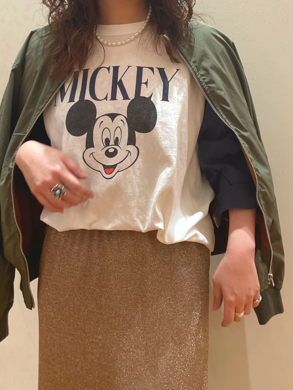 ホワイト系のTシャツ/カットソー、ベージュ系のスカート、グリーン系のブルゾンを着用したレディースの春コーディネートの4枚目の写真