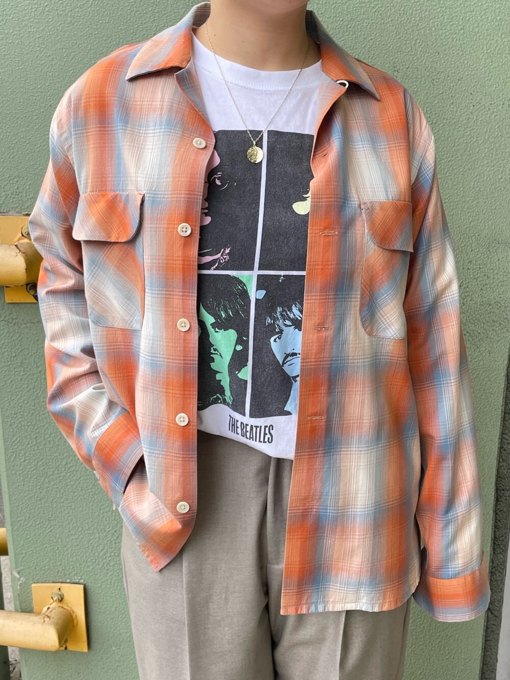 ホワイト系のTシャツ/カットソー、オレンジ系のシャツ/ブラウス、ベージュ系のスラックスを着用したレディースの冬コーディネートの4枚目の写真