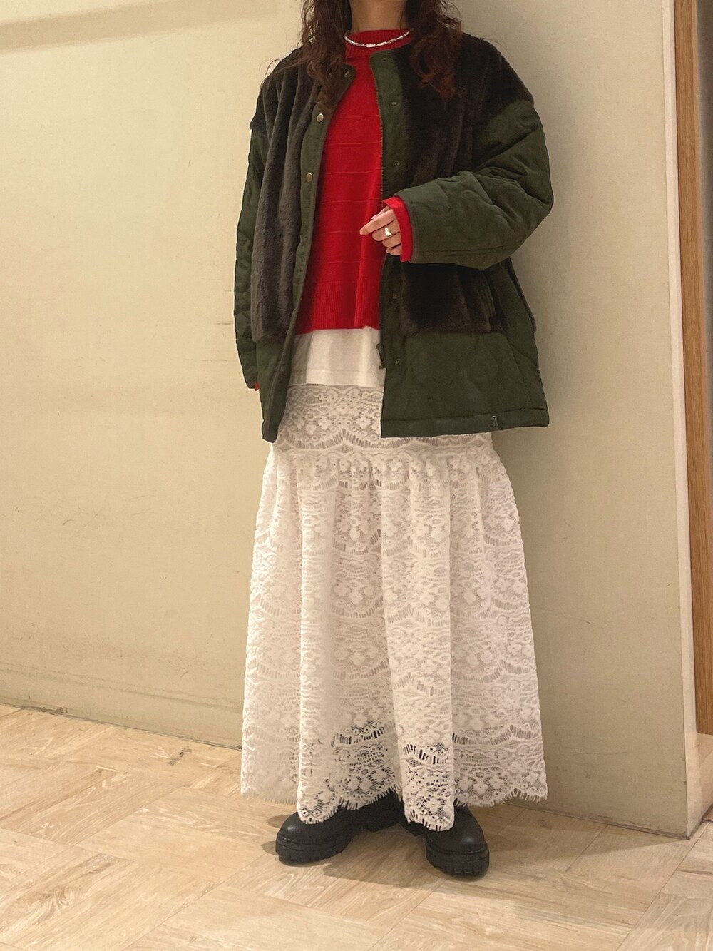 グリーン系のブルゾン、レッド系のニット/セーター、ホワイト系のスカートを着用したレディースの冬コーディネートの3枚目の写真