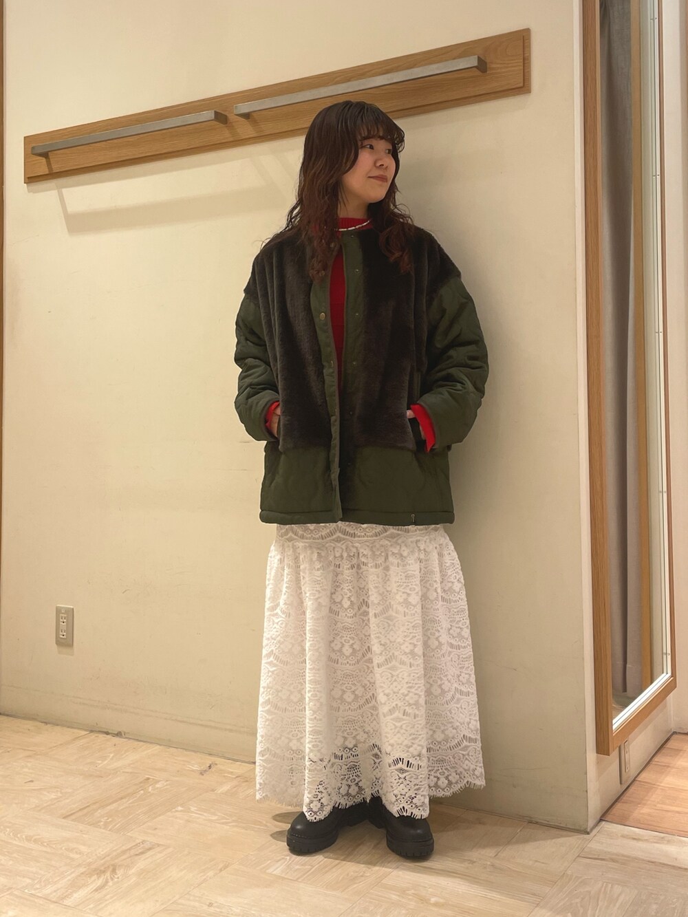 グリーン系のブルゾン、レッド系のニット/セーター、ホワイト系のスカートを着用したレディースの冬コーディネートの2枚目の写真