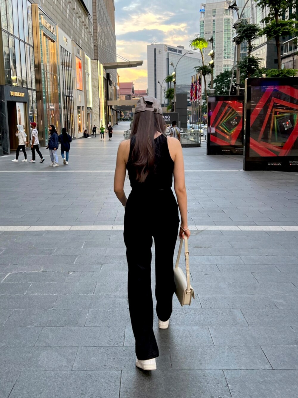 ブラック系のパンツ、ホワイト系のスニーカー、ベージュ系のキャップを着用したレディースの春コーディネートの2枚目の写真