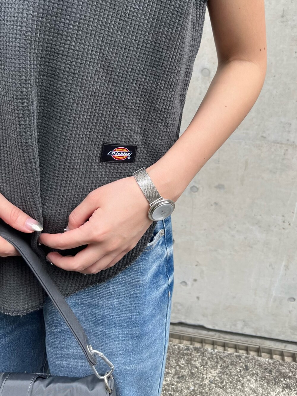 グレー系のトップス、ブルー系のデニムパンツ、シルバー系のパンプスを着用したレディースの春コーディネートの4枚目の写真