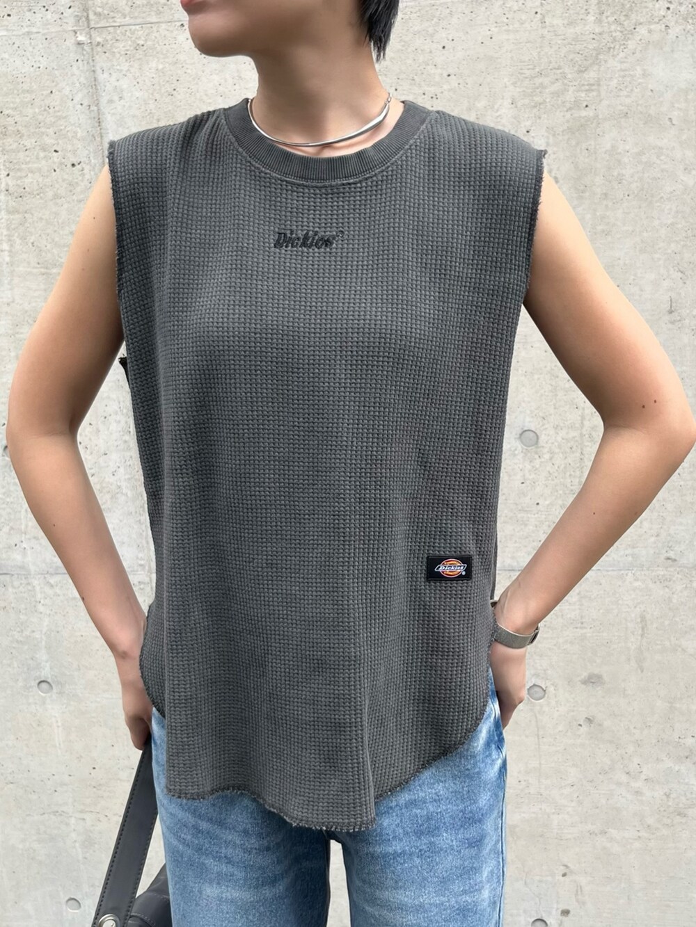 グレー系のトップス、ブルー系のデニムパンツ、シルバー系のパンプスを着用したレディースの春コーディネートの2枚目の写真