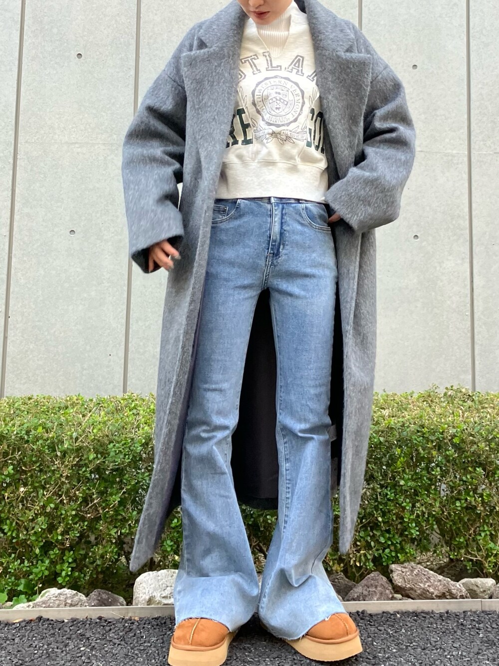 ブルー系のデニムパンツ、グレー系のチェスターコート、ホワイト系のスウェットを着用したレディースの冬コーディネートの4枚目の写真