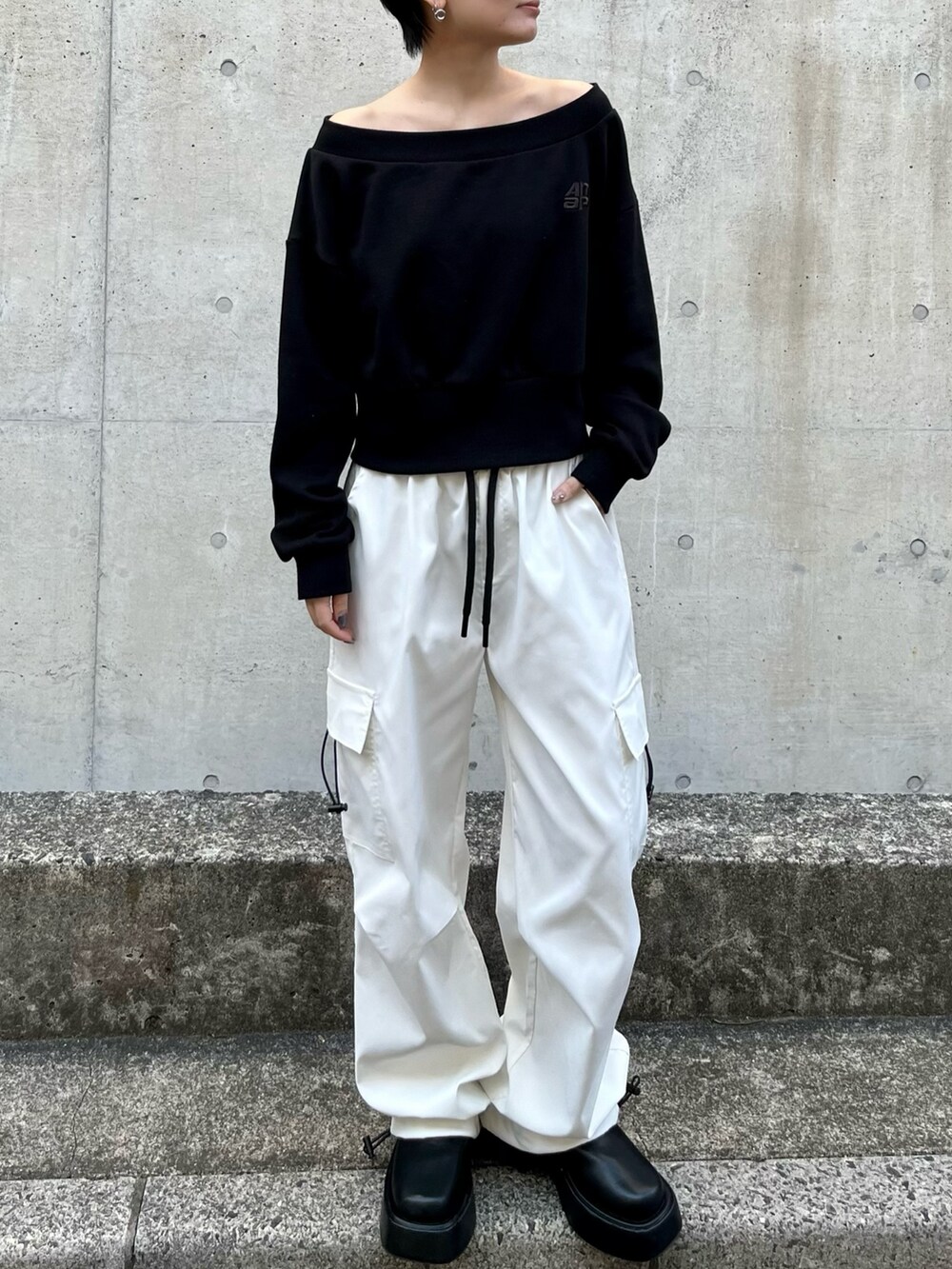 ブラック系のスウェット、ホワイト系のカーゴパンツ、ブラック系のブーツを着用したレディースの春コーディネートの3枚目の写真
