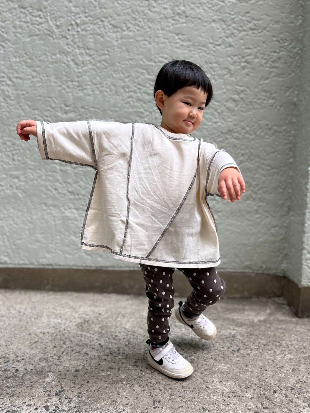 ブラック系のパンツ、ホワイト系のスニーカー、ベージュ系のTシャツ/カットソーを着用したキッズの春コーディネートの3枚目の写真