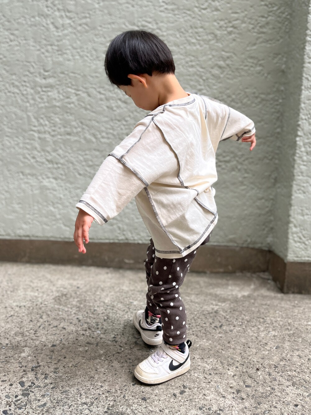 ブラック系のパンツ、ホワイト系のスニーカー、ベージュ系のTシャツ/カットソーを着用したキッズの春コーディネートの2枚目の写真