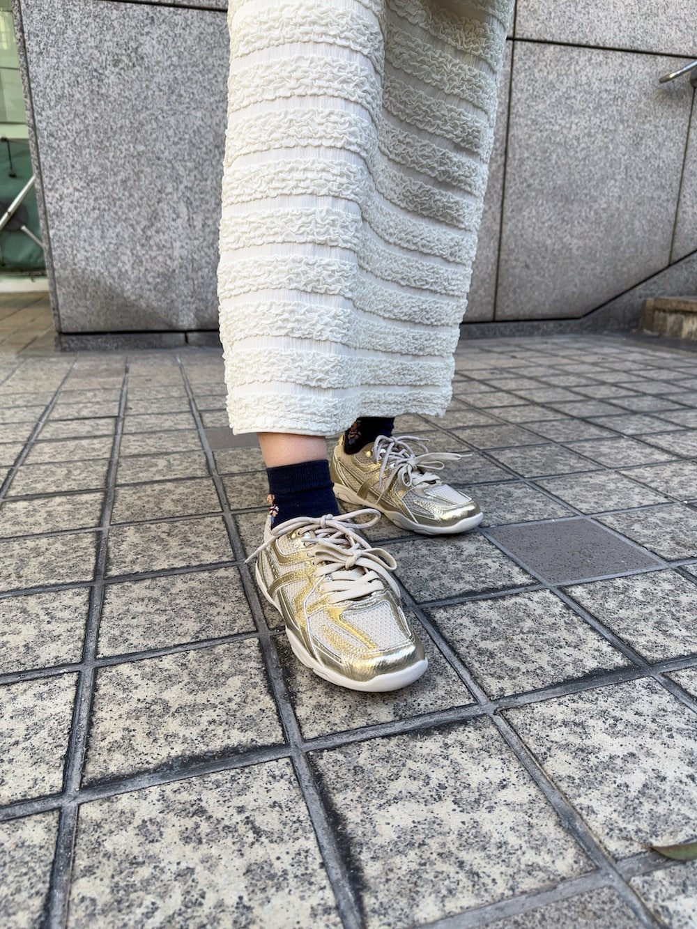 ゴールド系のスニーカー、その他のカーディガン/ボレロ、ホワイト系のスカートを着用したレディースの冬コーディネートの2枚目の写真