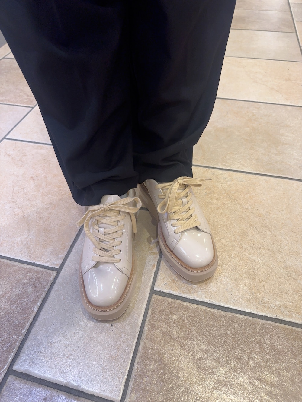 ベージュ系のスニーカー、ブラウン系のジャケット/アウター、ブラック系のスラックスを着用したレディースの秋コーディネートの2枚目の写真