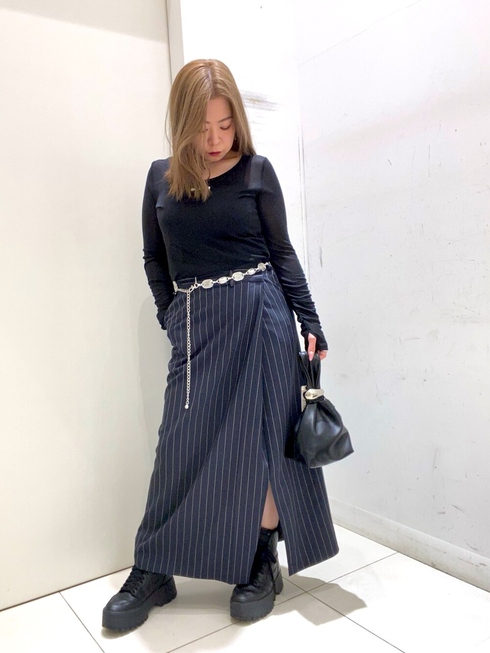 ブラック系のTシャツ/カットソー、ブルー系のスカート、ブラック系のハンドバッグを着用したレディースの春コーディネートの2枚目の写真