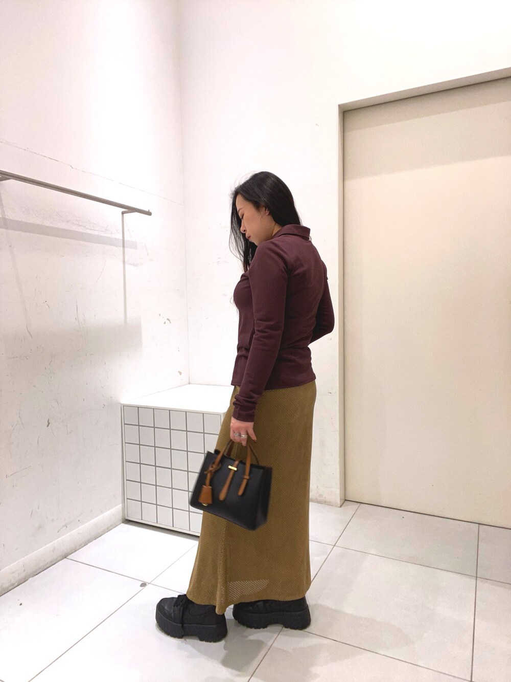 ブラウン系のシャツ/ブラウス、ベージュ系のスカート、ブラック系のハンドバッグを着用したレディースの冬コーディネートの2枚目の写真